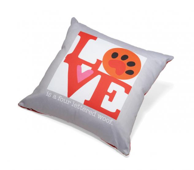 Gray pillow with colorful 'LOVE is a four-lettered woOF' text design on a white background