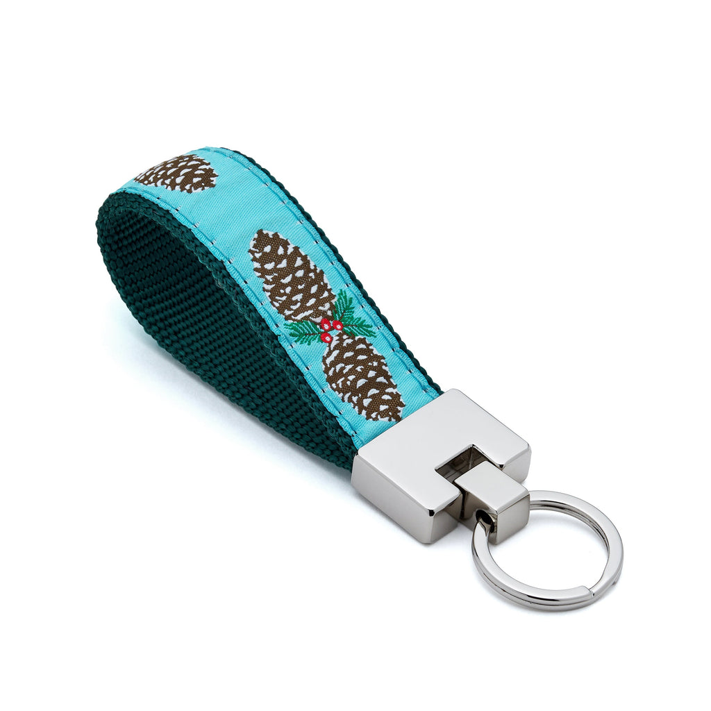 Keychain with pine cone design on a blue and green strap against a white background holiday christmas winter holly